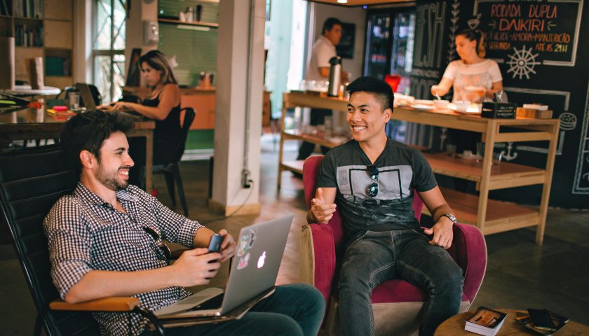 Two men enjoying a relaxed conversation with laptops in a cozy Brazilian café.