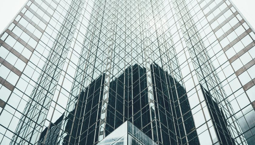 Striking low angle view of a modern skyscraper with reflective glass facade in a cityscape.
