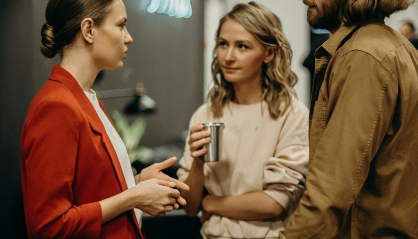 Three colleagues having a discussion in a modern office setting.
