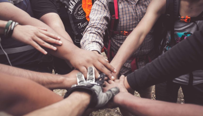 A group of diverse individuals join hands for teamwork in West Java, Indonesia.