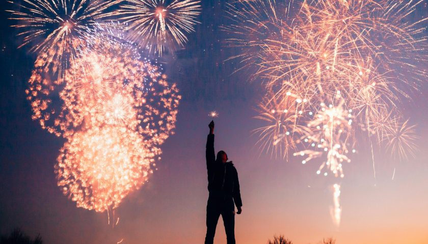 A person celebrates under vibrant fireworks in the evening sky in Kragujevac, Serbia.