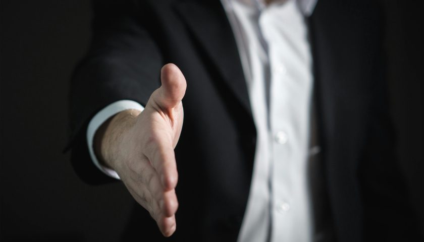 Close-up of a businessman extending hand for a handshake, symbolizing agreement and partnership.