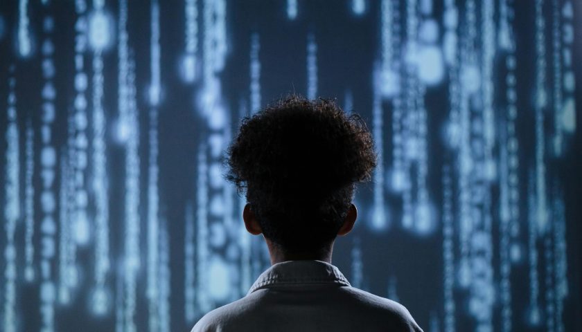 A young boy viewing a digital screen with data streams, symbolizing technology interaction.